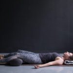 Woman doing a yoga pose with a bolster for support