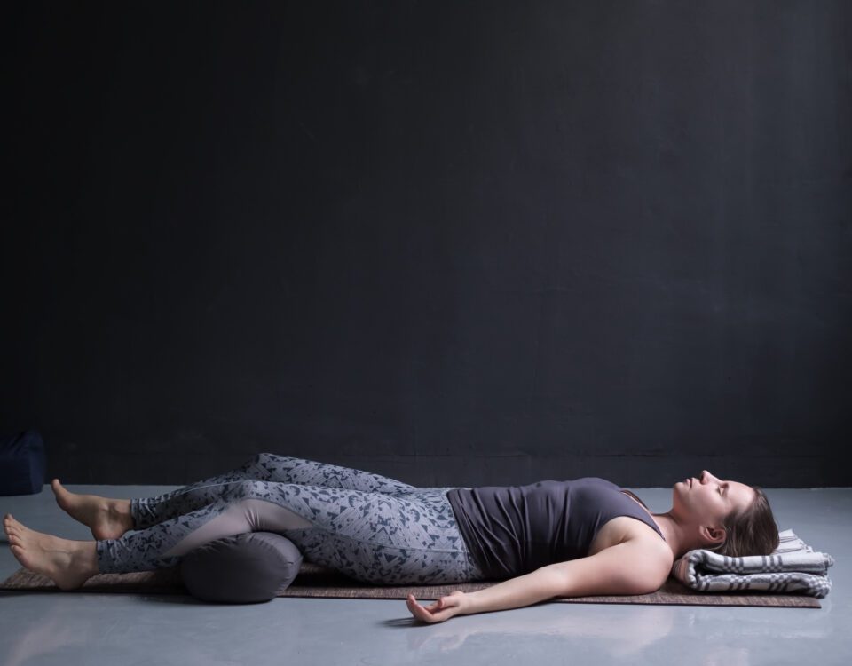 Frau, die eine Yogapose mit einem Bolster zur Unterstützung praktiziert