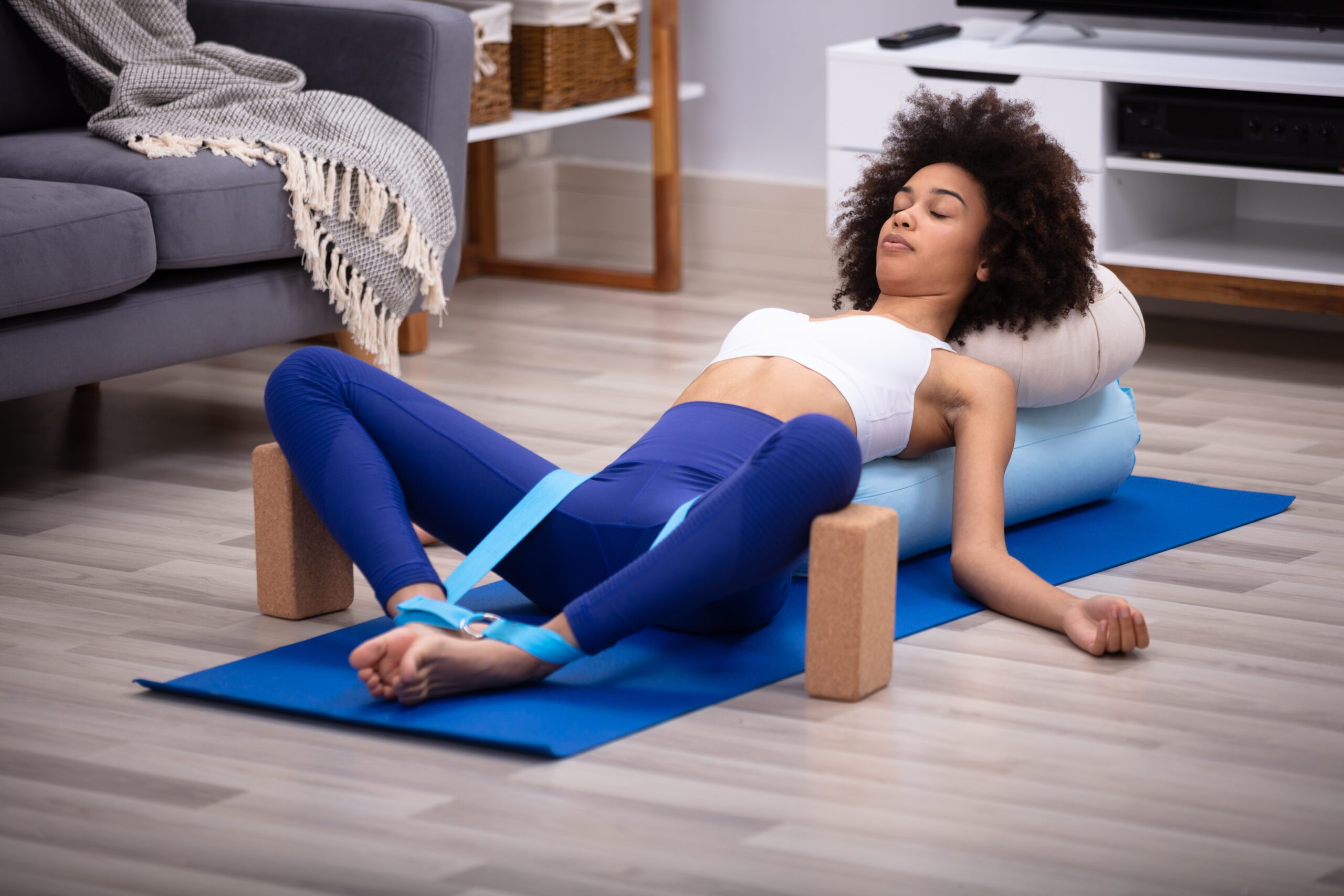 Yogi che esegue una posizione yoga avanzata con l'aiuto di un bolster